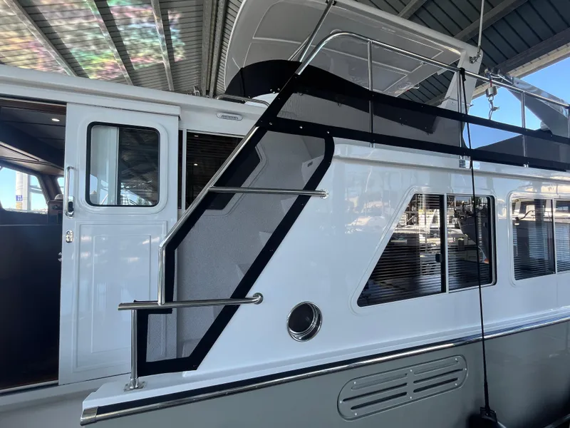 Slide: The Image of 2025 Helmsman Trawlers 43E Pilothouse yacht exterior with stairs and windows in a marina. - 29