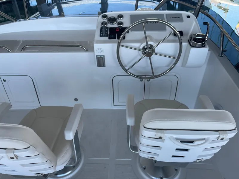 Slide: The Image of Helmsman Trawlers 43E Pilothouse 2025 helm with steering wheel and navigation controls. - 32