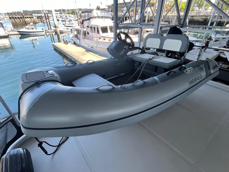 Slide: The Image of Inflatable boat docked near Helmsman Trawlers 43E Pilothouse, 2025 model, in a marina setting. - 34