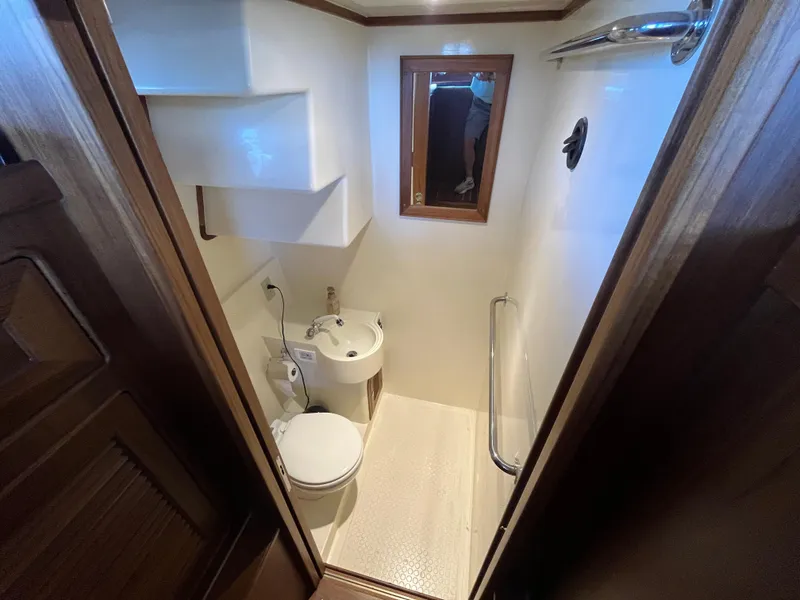 Slide: The Image of Compact bathroom in 2025 Helmsman Trawlers 43E PILOTHOUSE with toilet, sink, and mirror. - 6