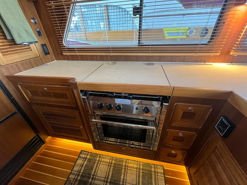 Slide: The Image of 2025 Helmsman Trawlers 43E PILOTHOUSE kitchen with wood cabinetry and stainless steel oven. - 9
