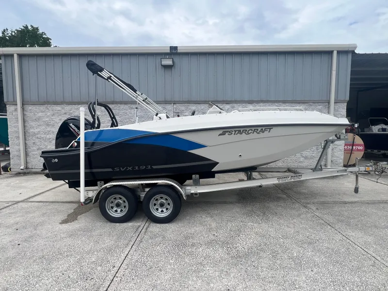 Slide: The Image of 2022 Starcraft SVX 191 OB boat on trailer, parked outside a metal building. - 1