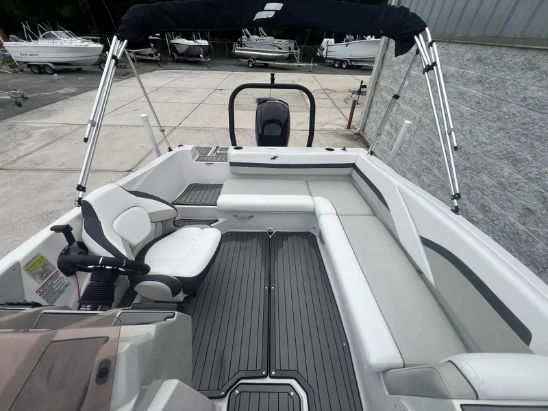 Slide: The Image of 2022 Starcraft SVX 191 OB boat interior with seating and steering wheel, docked outdoors. - 14
