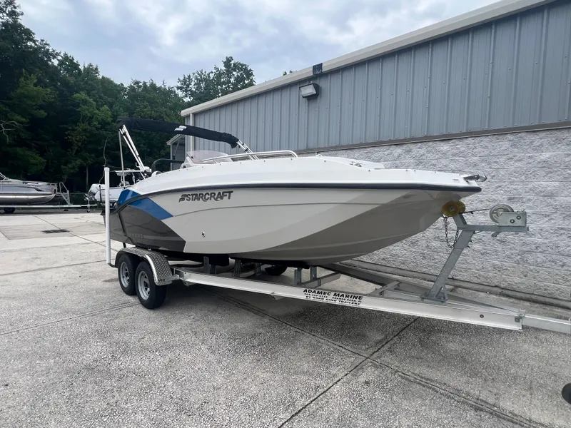 Slide: The Image of 2022 Starcraft SVX 191 OB boat on trailer, parked outdoors near a building. - 2