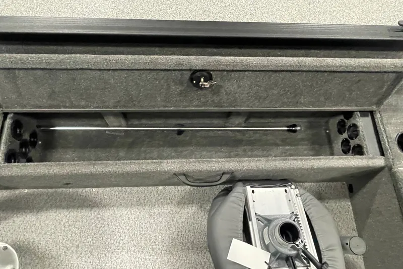 Slide: The Image of 2026 Alumacraft Voyageur 175 Tiller interior storage compartment with rod holders and seat base. - 11