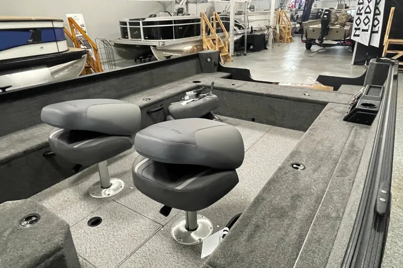 Slide: The Image of 2026 Alumacraft Voyageur 175 Tiller interior with two gray seats in a showroom. - 5