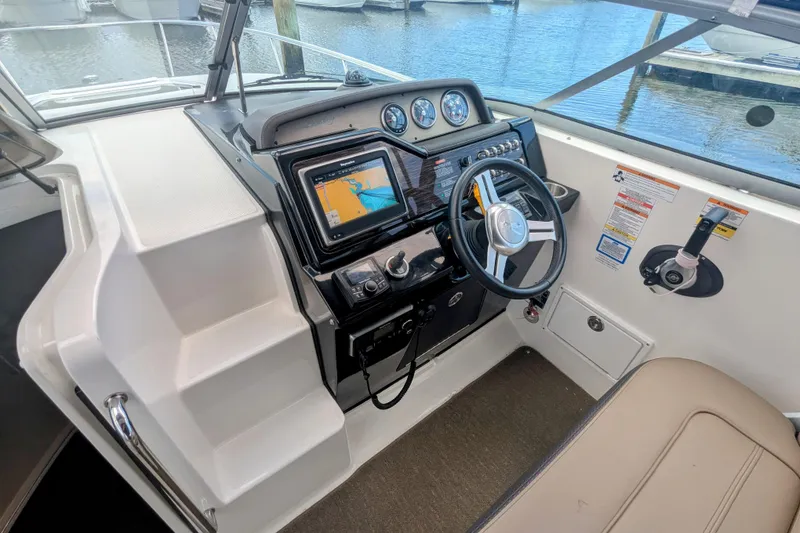 Slide: The Image of 2017 Sea Ray Sundancer 280 helm with navigation system and steering wheel, docked by the water. - 11