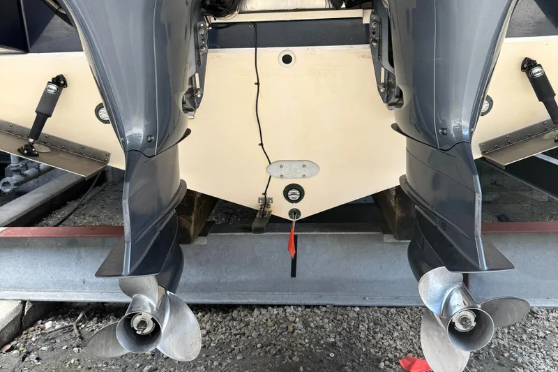 Slide: The Image of Twin outboard motors on a 2013 Pursuit 365i Sport Coupe boat, docked on gravel. - 28