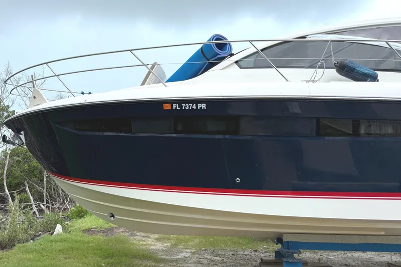 Slide: The Image of 2013 Pursuit 365i Sport Coupe boat on land, blue hull, red stripe, registration FL 7374 PR. - 3