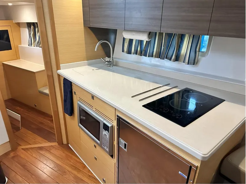 Slide: The Image of 2013 Pursuit 365i Sport Coupe interior kitchen with stove, microwave, and wood cabinetry. - 6