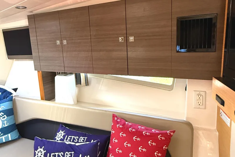 Slide: The Image of Interior of 2013 Pursuit 365i Sport Coupe with wooden cabinets and nautical-themed cushions. - 9