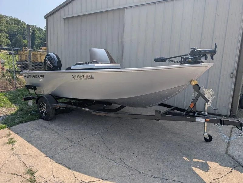 The Image of 2026 Starcraft 166 Starfish boat on trailer, parked beside a metal building. - 1