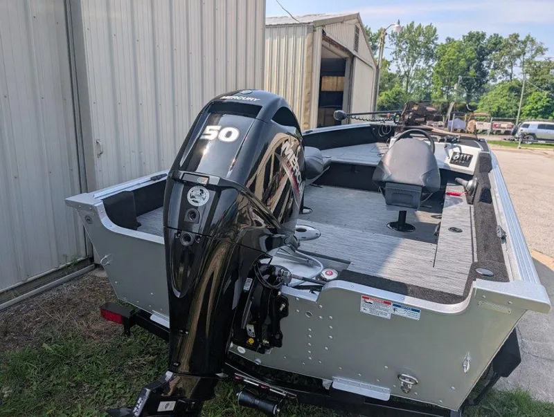 Slide: The Image of 2026 Starcraft 166 Starfish boat with Mercury 50 outboard motor, parked near a metal building. - 3