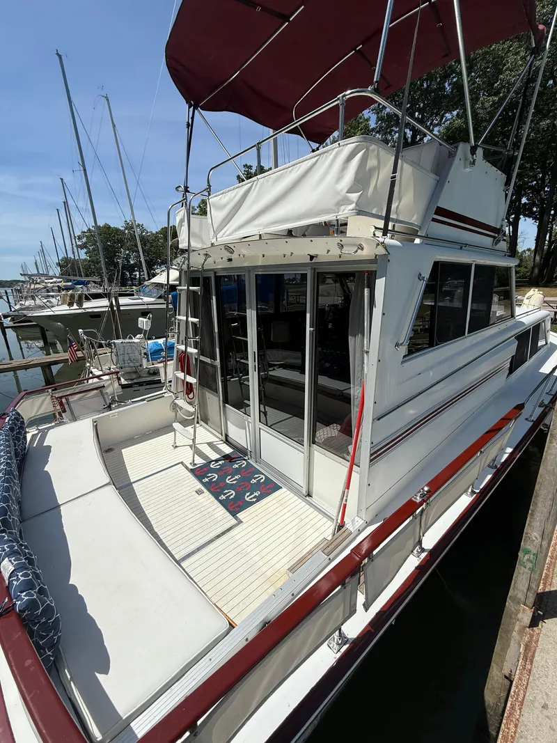 Slide: The Image of 1985 Marinette 32 Sedan boat docked, featuring a spacious deck and canopy. - 10