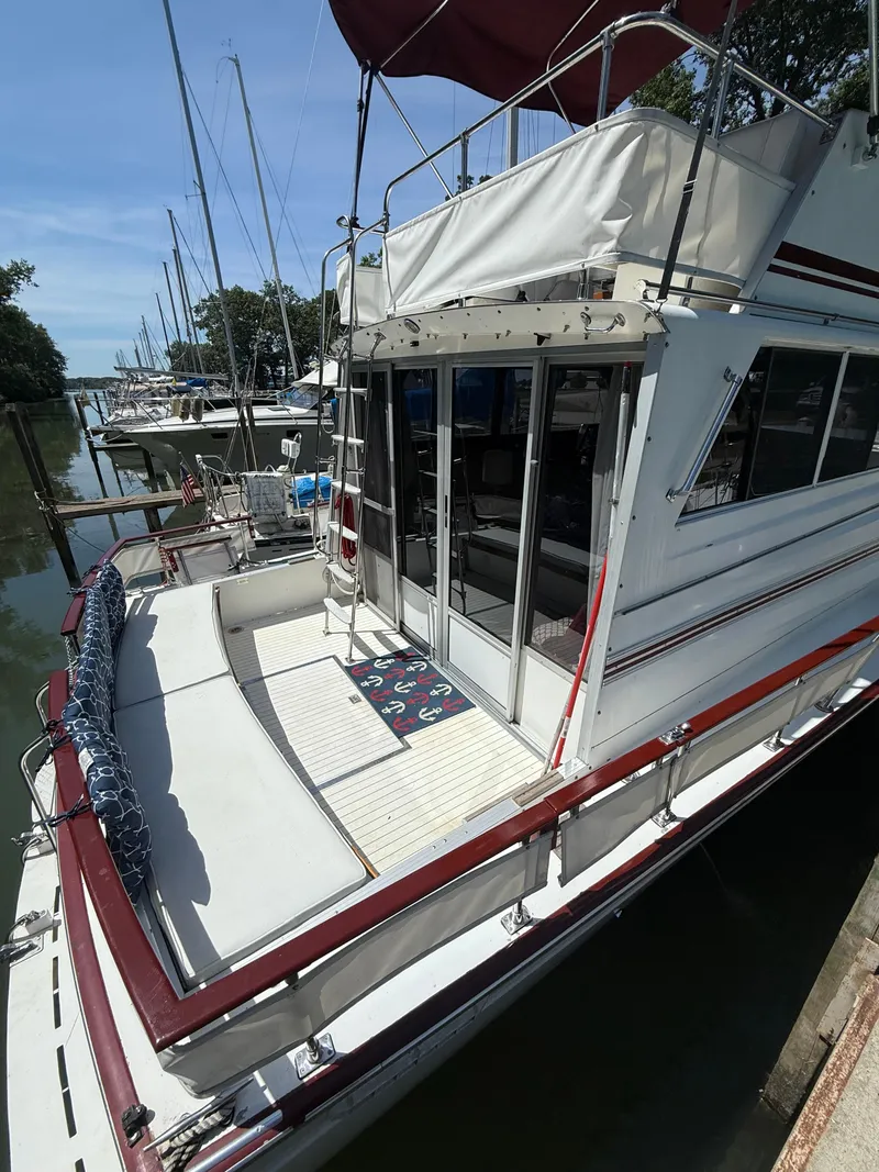 Slide: The Image of 1985 Marinette 32 Sedan docked, featuring spacious deck and glass doors, under clear blue sky. - 11