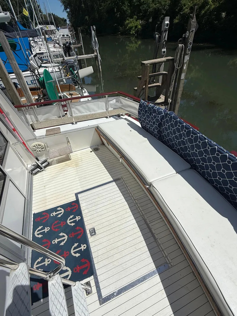 Slide: The Image of 1985 Marinette 32 Sedan boat deck with seating, docked by a calm river. - 12