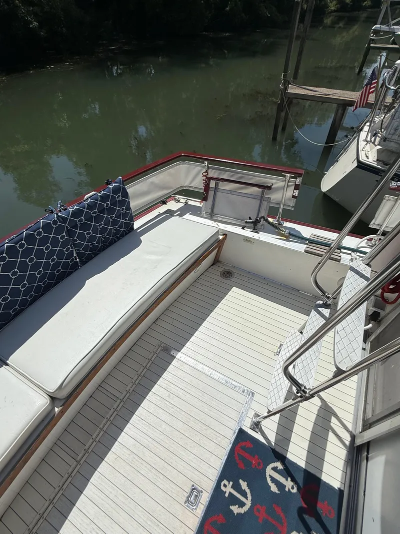 Slide: The Image of 1985 Marinette 32 Sedan boat deck with seating, nautical-themed rug, and water view. - 13