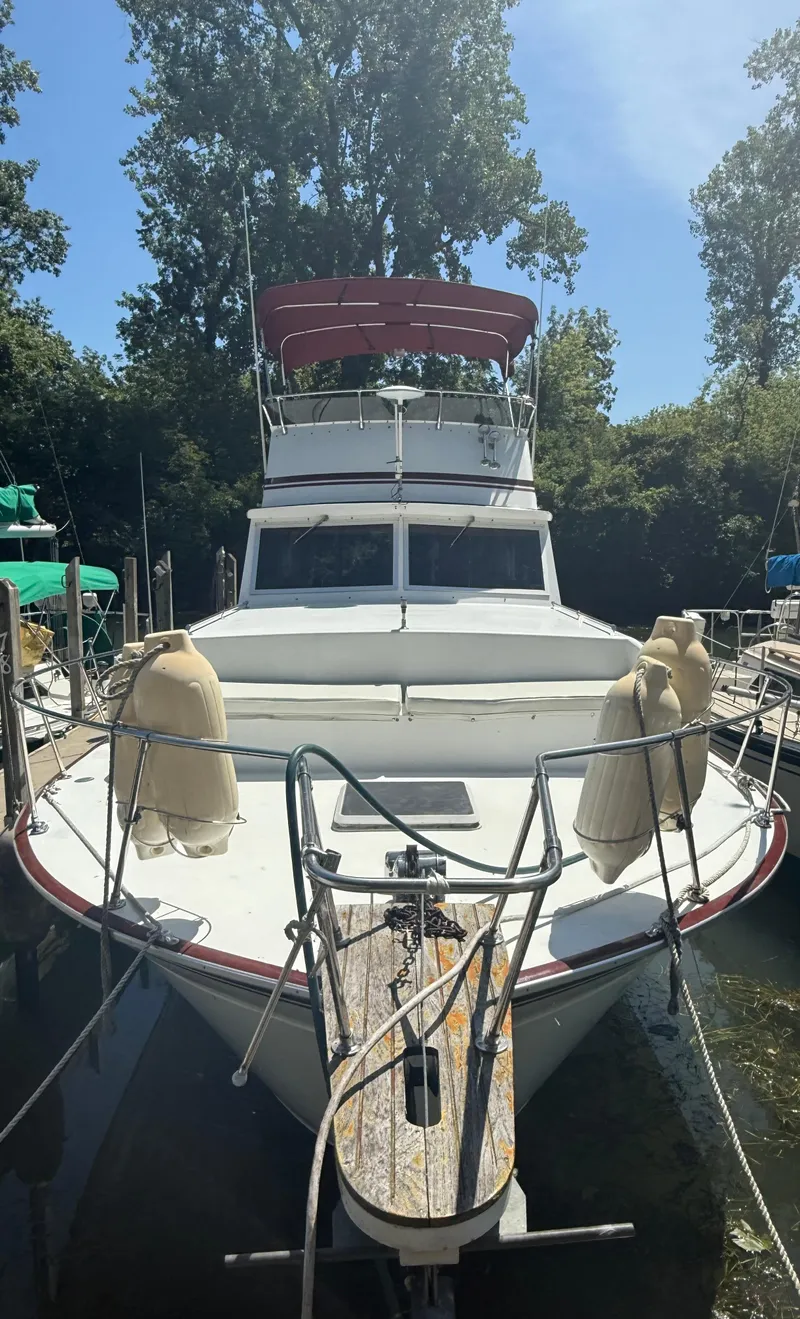 Slide: The Image of 1985 Marinette 32 Sedan boat docked, front view with trees in background. - 2