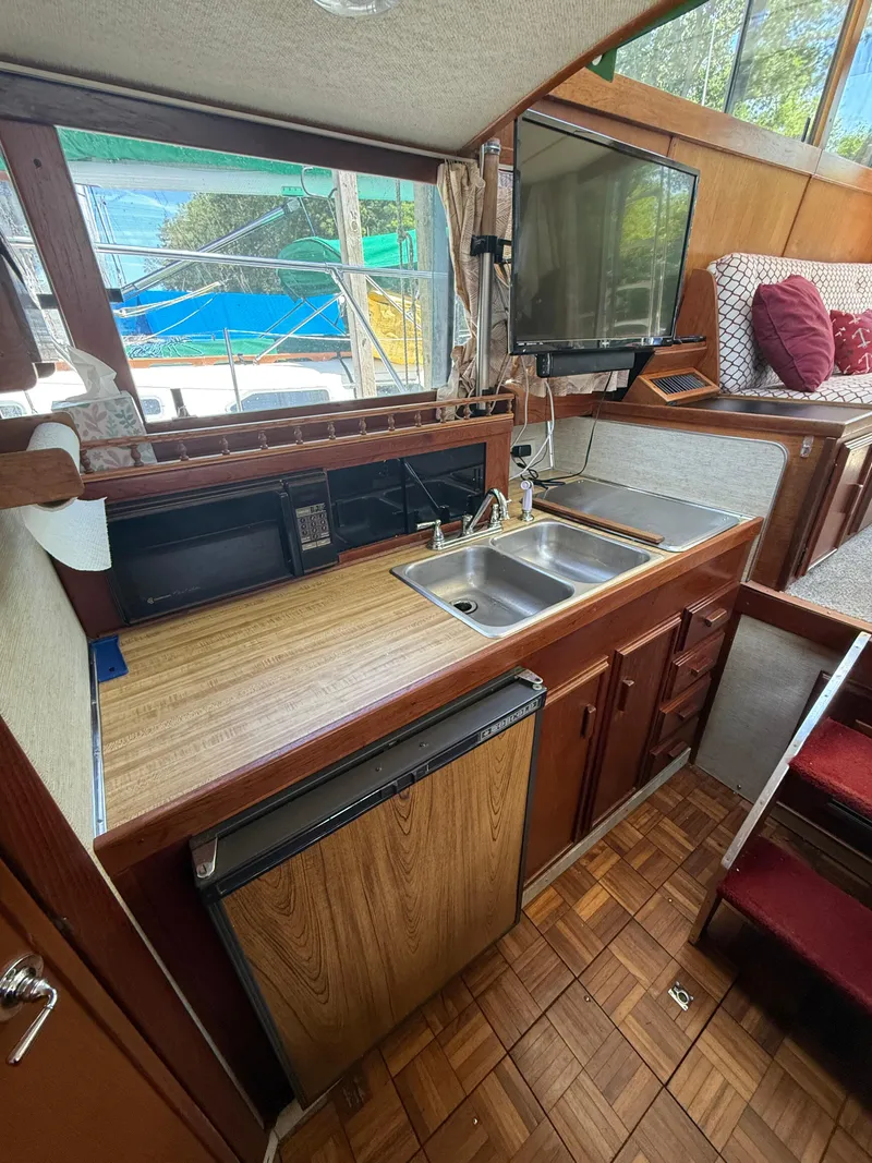 Slide: The Image of 1985 Marinette 32 Sedan kitchen with wood cabinets, sink, and TV. - 22