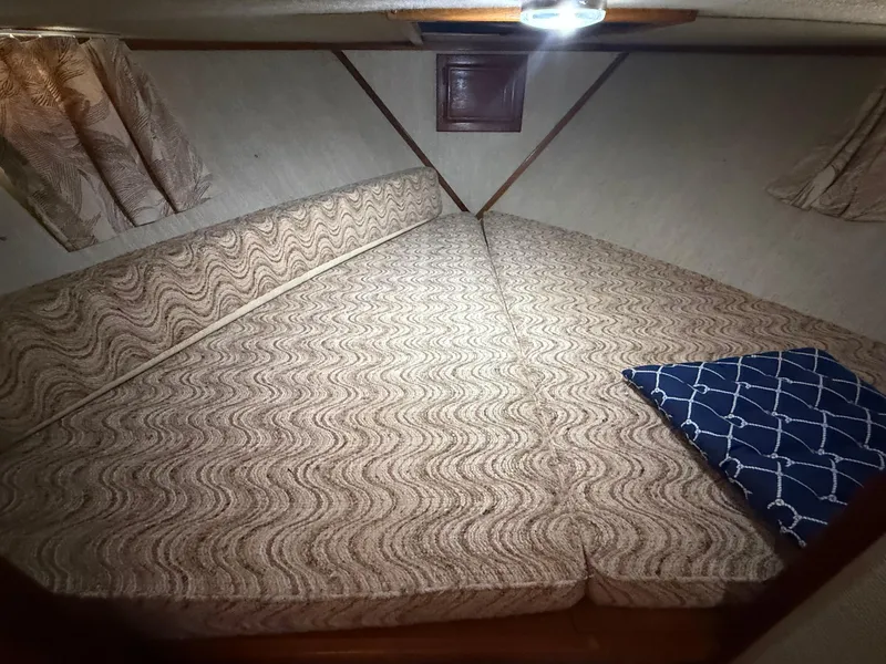 Slide: The Image of 1985 Marinette 32 Sedan cabin interior with patterned bedding and curtains. - 25