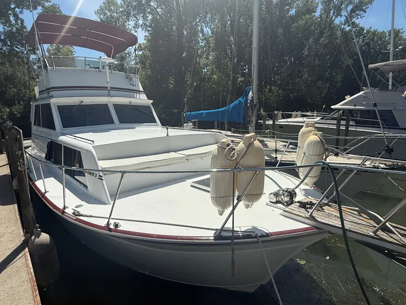 Slide: The Image of 1985 Marinette 32 Sedan boat docked, featuring a white exterior and red canopy. - 3