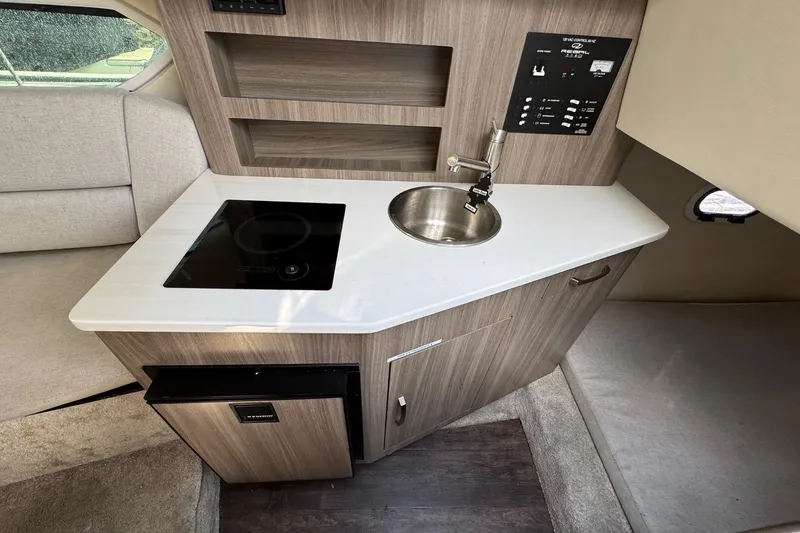 Slide: The Image of 2023 Regal 26 XO boat interior with kitchenette, featuring sink, stove, and control panel. - 22