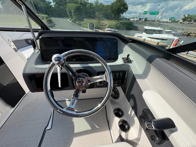 Slide: The Image of 2025 Regal LX4 boat helm with steering wheel, dashboard, and controls, docked near marina. - 17