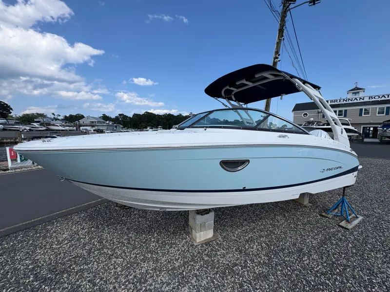 Slide: The Image of 2025 Regal LX4 boat displayed outdoors on a stand, under a clear blue sky. - 3