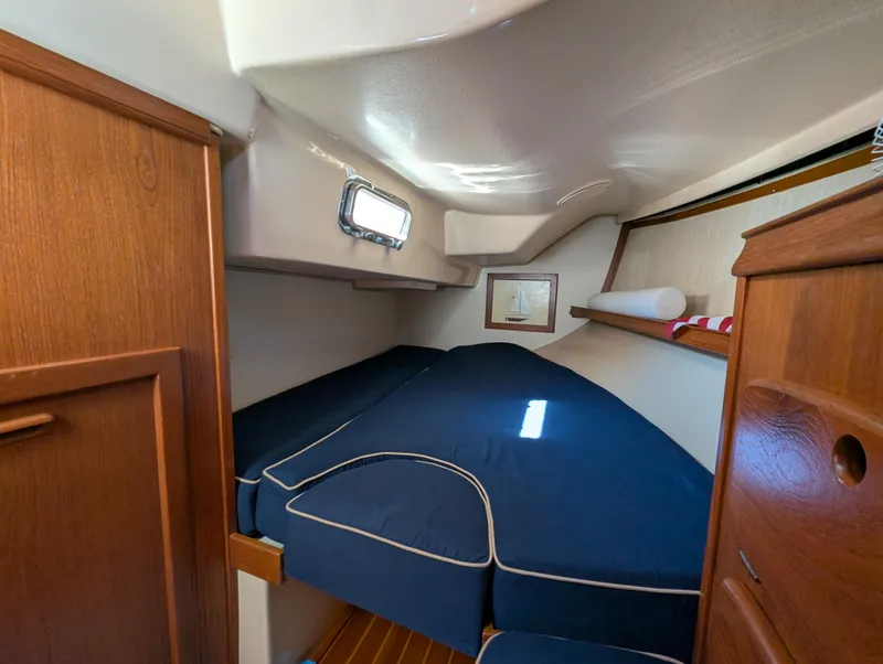 Slide: The Image of 1994 Island Packet 35 sailboat cabin with blue bedding and wooden interior. - 33