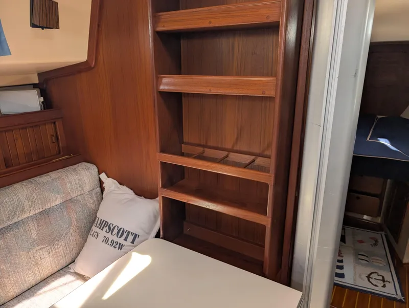 Slide: The Image of Interior of a 1994 Island Packet 35 sailboat with wooden shelves and seating area. - 36