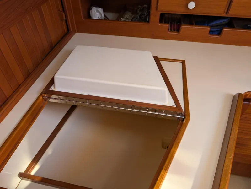 Slide: The Image of Interior of 1994 Island Packet 35 sailboat with wooden cabinetry and storage compartment. - 38