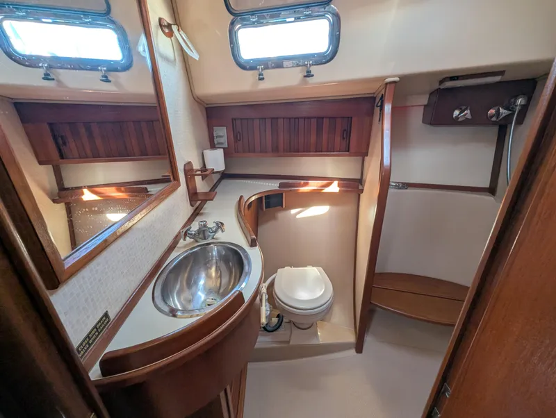 Slide: The Image of 1994 Island Packet 35 yacht bathroom with sink, toilet, and wooden cabinetry. - 40