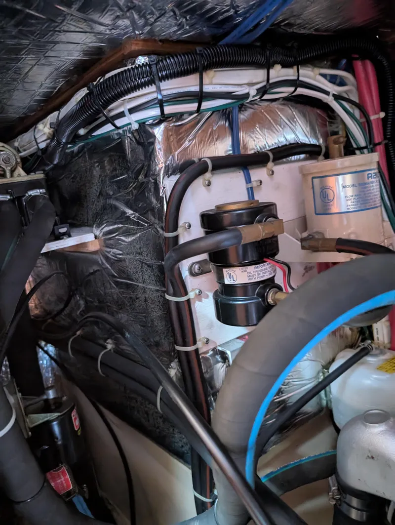 Slide: The Image of Engine compartment of a 1994 Island Packet 35 sailboat, showcasing wiring and mechanical components. - 48