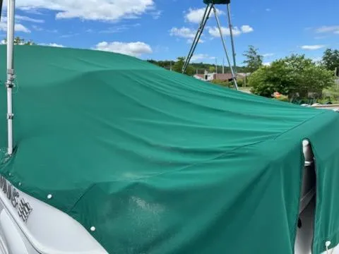 Slide: The Image of 2001 Four Winns 248 Vista boat with green cover under blue sky. - 10