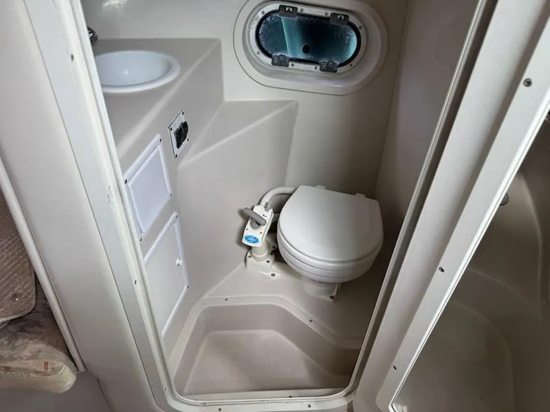 Slide: The Image of 2001 Four Winns 248 Vista boat bathroom with toilet, sink, and porthole window. - 20