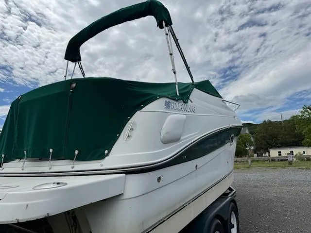 Slide: The Image of 2001 Four Winns 248 Vista boat with green canopy on trailer, under cloudy sky. - 7