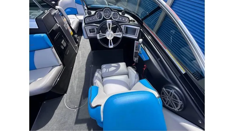 Slide: The Image of 2017 MasterCraft X23 boat interior with blue and white seating, modern dashboard, and steering wheel. - 12