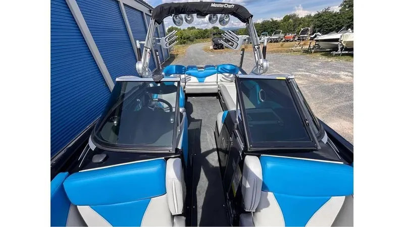 Slide: The Image of 2017 MasterCraft X23 boat interior with blue and white seating, open windshield, and wakeboard tower. - 14
