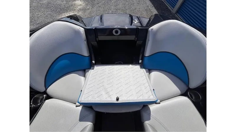 Slide: The Image of 2017 MasterCraft X23 boat interior with gray and blue seating, featuring a central table. - 15