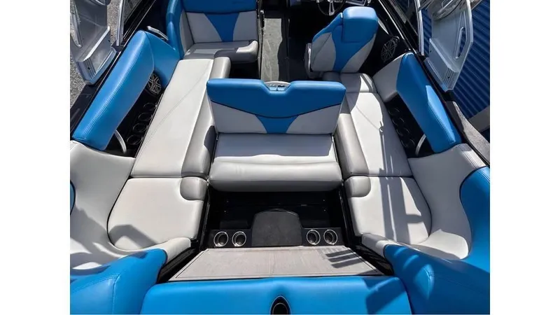 Slide: The Image of 2017 MasterCraft X23 boat interior with blue and gray seating, cup holders, and spacious layout. - 17