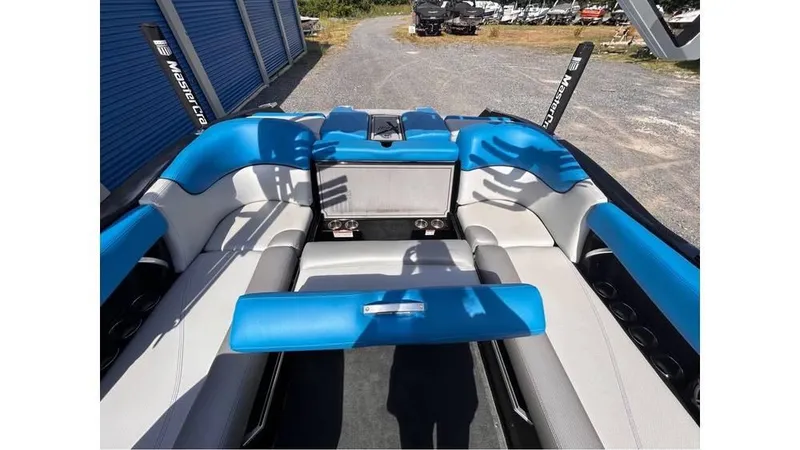 Slide: The Image of 2017 MasterCraft X23 boat interior with blue and gray seating, parked outdoors. - 18