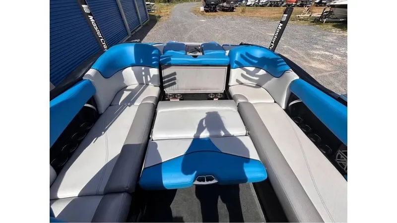 Slide: The Image of 2017 MasterCraft X23 boat interior with blue and gray seating, outdoor setting. - 19