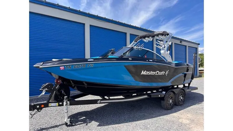 Slide: The Image of 2017 MasterCraft X23 boat on trailer, parked near blue storage units. - 6