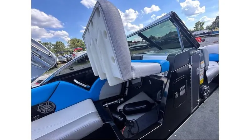 Slide: The Image of 2017 MasterCraft X23 boat interior with blue and white seating, open storage, and clear skies. - 7