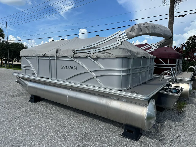Slide: The Image of 2025 Sylvan Mirage 818 Cruise pontoon boat with cover, parked outdoors on a sunny day. - 0