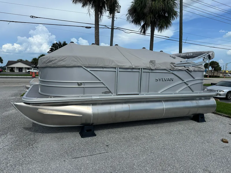 Slide: The Image of 2025 Sylvan Mirage 818 Cruise pontoon boat with cover, parked on pavement. - 1