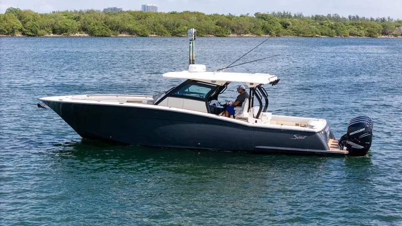 Slide: The Image of 2020 Scout 380 LXF boat on water, side view with lush greenery in background. - 1