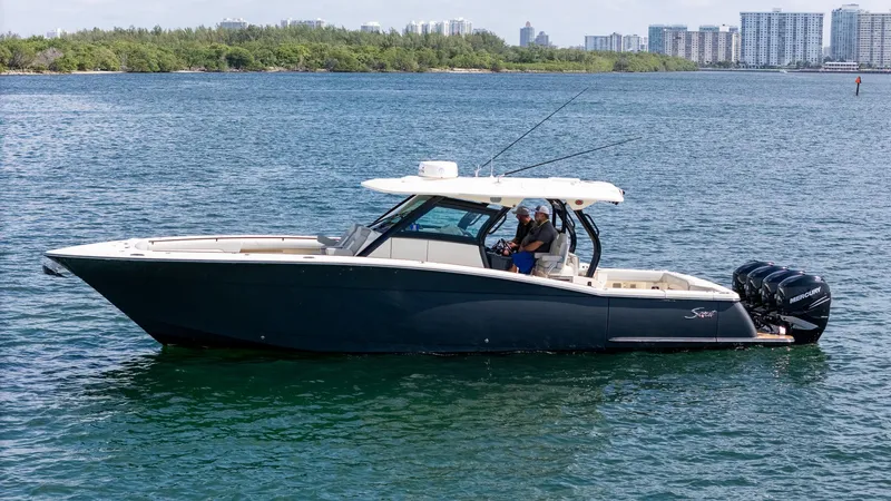 Slide: The Image of 2020 Scout 380 LXF boat on water with city skyline in background. - 12