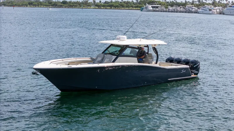 Slide: The Image of 2020 Scout 380 LXF boat cruising on a calm, scenic waterway. - 13