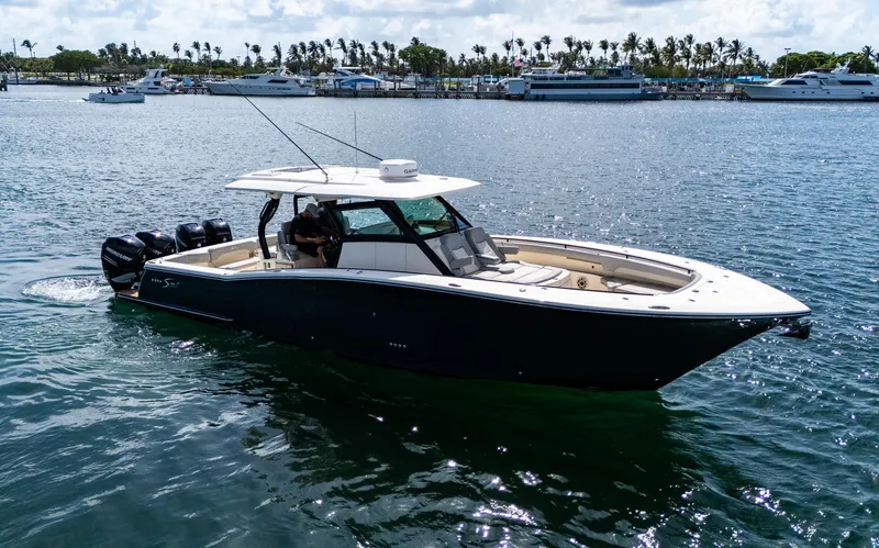Slide: The Image of 2020 Scout 380 LXF boat cruising on a sunny day near a marina. - 2